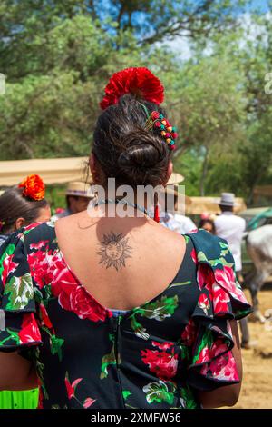 Donna girata indossando il tipico costume da rociero e fiori nei capelli, durante la celebrazione del pellegrinaggio di El Rocio ad Almonte, in spagna Foto Stock