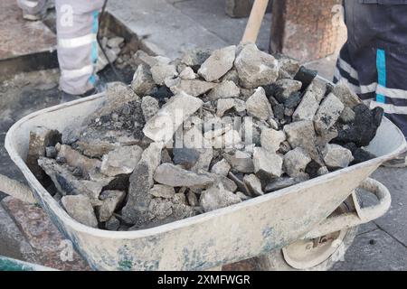 Un gruppo di operai edili che spostano una carriola carica di macerie in un cantiere edile Foto Stock