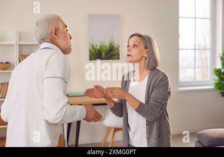 Una coppia anziana e anziana che litigano nel salotto di casa. Foto Stock