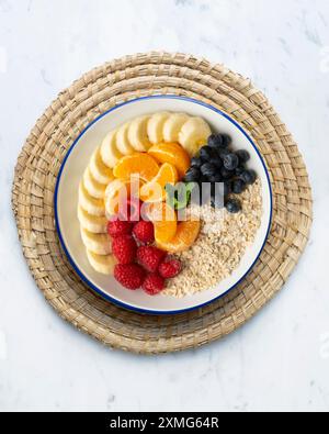 Deliziosa e sana ciotola di farina d'avena con mandarino, banana, mirtilli e lamponi. Foto Stock