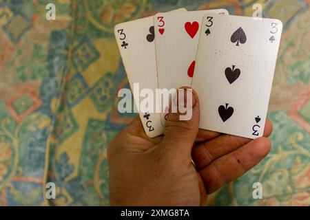 tre carte da gioco con il numero tre in mano umana Foto Stock