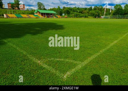 Una vista ad angolo di un campo da calcio con erba verde e posti vuoti sullo sfondo in una giornata di sole. Foto Stock