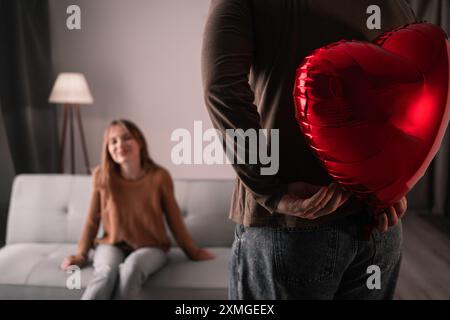 Bella giovane coppia innamorata dei palloncini a forma di cuore che celebrano San Valentino a casa Foto Stock