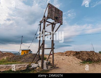 Il canestro da basket della comunità si erge alto in una baraccopoli filippina tra strutture incompiute e cielo coperto Foto Stock