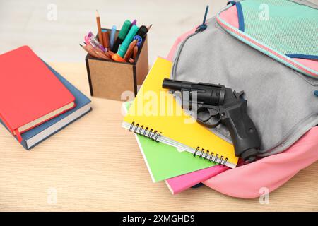 Cancelleria scolastica e pistola su scrivania di legno, primo piano Foto Stock