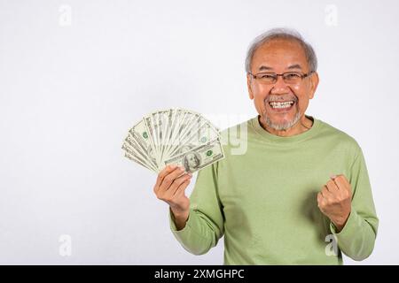 Ritratto vecchio asiatico sorridente sta tenendo in mano un mucchio di banconote in studio girato isolato su bianco Foto Stock