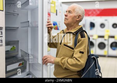 Pensionato Senor MAN che acquista un frigorifero nello showroom del negozio di elettrodomestici Foto Stock