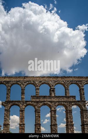 Storico acquedotto romano a Segovia, Castilla y Leon, Spagna. Con archi in pietra e un cielo blu con nuvole. Foto Stock