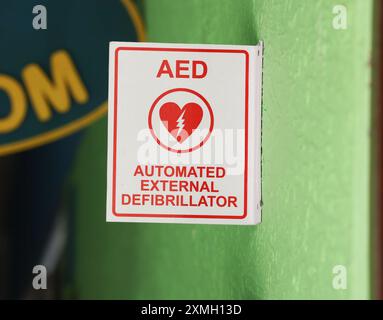 Logo del defibrillatore elettrico su un cartello in un ambiente urbano, che indica la presenza vicina di un dispositivo semiautomatico esterno, Foto Stock