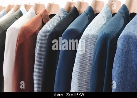 Una fila di giacche bianche e blu appese su un rack. Le giacche sono tutte di colori e stili diversi Foto Stock