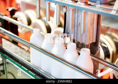 Trasportatore industriale con flaconi in plastica sulla linea di erogazione Foto Stock