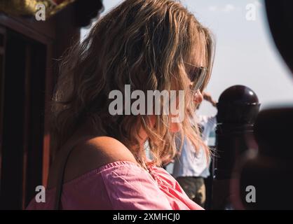 Donna rilassante con gli occhiali da sole che si gode una giornata d'estate in un panoramico lungomare Foto Stock