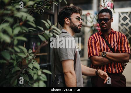 Due uomini d'affari in una discussione informale all'aperto con occhiali da sole e abbigliamento colorato Foto Stock