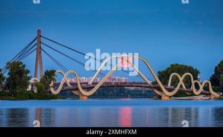Pink Full Moon sorge sullo sfondo di un ponte pedonale nel distretto di Obolon, Kiev, Ucraina Foto Stock