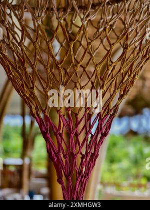 Elegante lampada in vimini sospesa da un soffitto in legno rustico Foto Stock