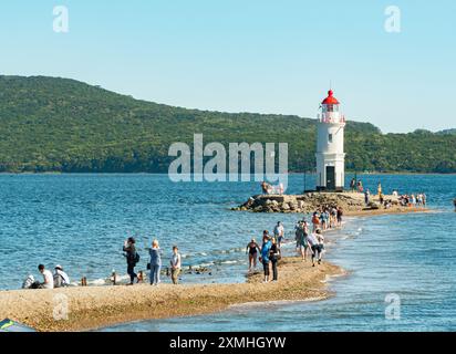Vladivostok, Russia - 1° settembre 2018: Vista delle persone che camminano lungo lo spiedo verso il faro di Tokarevsky al tramonto. Foto Stock