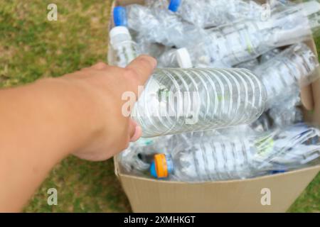 Tenere le mani e inserire i flaconi di plastica nella scatola marrone per rifiuti Foto Stock