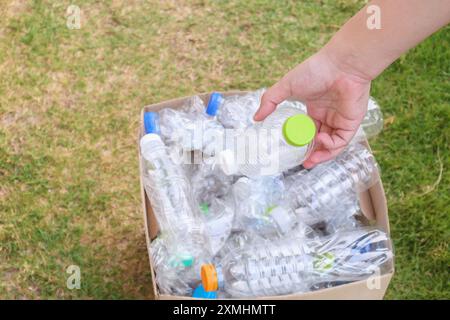 Tenere le mani e inserire i flaconi di plastica nella scatola marrone per rifiuti Foto Stock