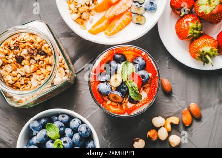 Colazione gourmet: Parfait di fragole, mirtilli e muesli con delicato yogurt greco, mascarpone e panna montata su fondo grigio Foto Stock