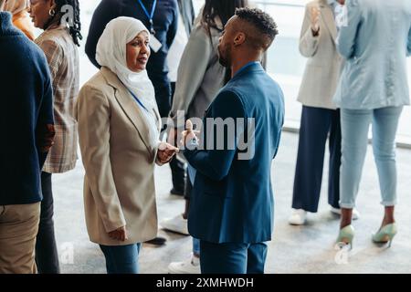 Un gruppo diversificato di professionisti che interagiscono in rete e interagiscono in occasione di una conferenza aziendale. Le persone sono impegnate in conversazioni e creano connessioni Foto Stock