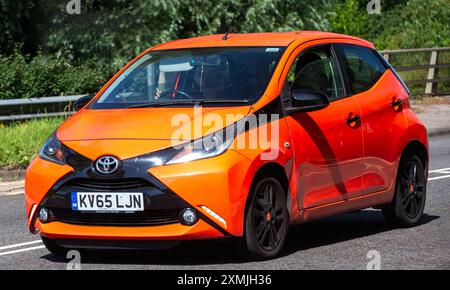 Milton Keynes, Regno Unito - 28 luglio 2024: 2015 auto Toyota Aygo arancione che guida su una strada britannica Foto Stock