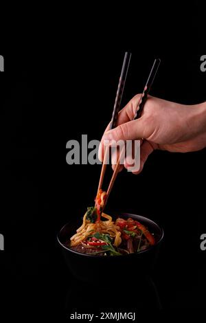 Mescolare le tagliatelle fritte con verdure e gamberetti in una ciotola nera. Sfondo ardesia. Vista dall'alto. Spazio di copia. Foto Stock