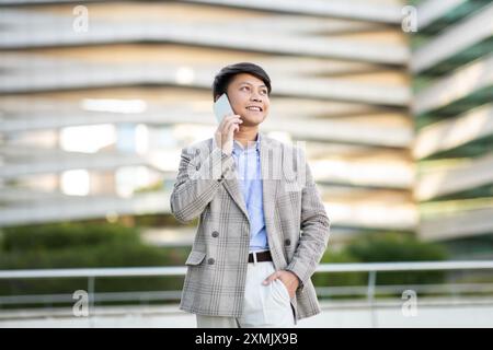 Giovane uomo che parla al cellulare di fronte all'edificio Foto Stock