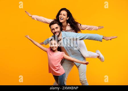 Felice famiglia che gioca aereo su sfondo giallo Foto Stock