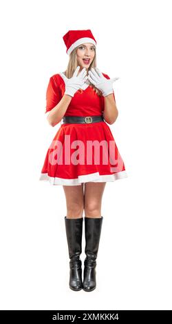 giovane donna latina bionda vestita in costume di babbo natale a tutta lunghezza, che guarda la fotocamera stupita su sfondo bianco Foto Stock