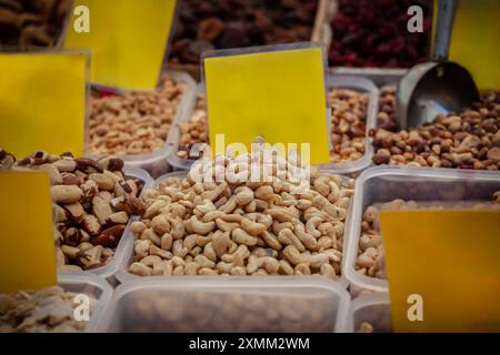 Una bancarella del mercato che espone anacardi in vendita. L'immagine mostra una varietà di noci disposte ordinatamente in contenitori con etichette, offrendo snack salutari Foto Stock