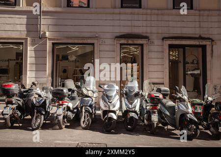 Questa fotografia mostra una linea di scooter parcheggiati lungo una strada di Roma, Italia, che mette in risalto la quintessenza della scena urbana di questa città storica. S Foto Stock