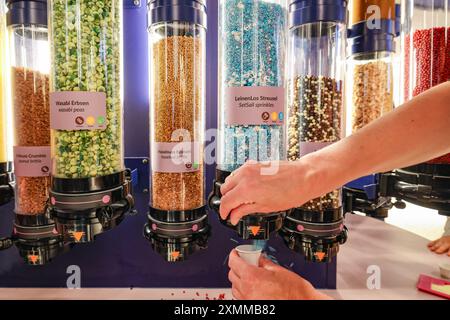 Amburgo, Germania. 25 luglio 2024. Un visitatore del Chocoversum Hamburg decora una tavoletta di cioccolato nel laboratorio di cioccolato. Durante un tour di 90 minuti, i visitatori apprenderanno molti fatti interessanti sul cacao. Diversi armadi forniscono informazioni su tutto, dalla coltivazione e commercio alla lavorazione del cacao, con degustazione e partecipazione espressamente incoraggiate. Crediti: Ulrich Perrey/dpa/Alamy Live News Foto Stock