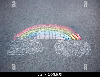 Disegno del gesso del marciapiede. Un arcobaleno e nuvole cielo dipinto sull'asfalto. Attività per bambini. Sfondo colorato con gesso. Spazio per le copie del parco giochi della scuola. Foto Stock