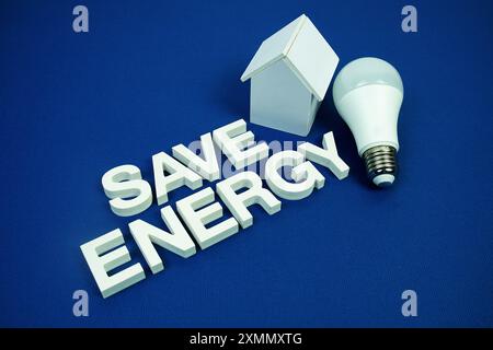 Risparmia energia lettere alfabetiche con il modello di casa e le lampadine a LED su sfondo blu navy, risparmiando e rispettando l'ambiente Foto Stock