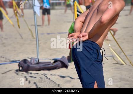 Un giocatore di Beach volley invia segnali a mano per comunicare con i compagni durante un'intensa partita 3x3. Questa immagine ricca di azione cattura la strategia Foto Stock