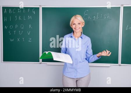 Foto di una donna anziana intelligente che lavora come docente spiega l'argomento della lezione isolato sullo sfondo del green board Foto Stock