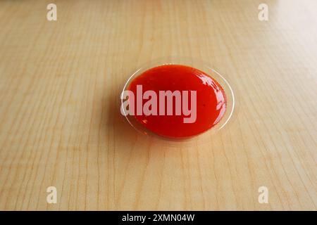 Una ciotola di salsa di pomodoro si trova su un tavolo di legno. Foto Stock