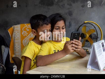 Ragazzo e ragazza del Bangladesh che usano uno smartphone nella baraccopoli di Korail, Divisione di Dacca, Dacca, Bangladesh Foto Stock