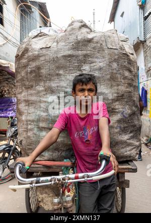 Ragazzo del Bangladesh che trasporta rifiuti da riciclare in bicicletta nella baraccopoli di Korail, Divisione di Dacca, Dacca, Bangladesh Foto Stock