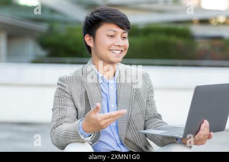 Giovane sorridente che utilizza un computer portatile all'aperto durante il giorno Foto Stock