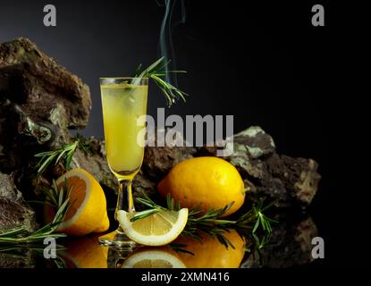 Limoncello liquoroso tradizionale italiano con fettine di limone e rametto rosmarino. Foto Stock