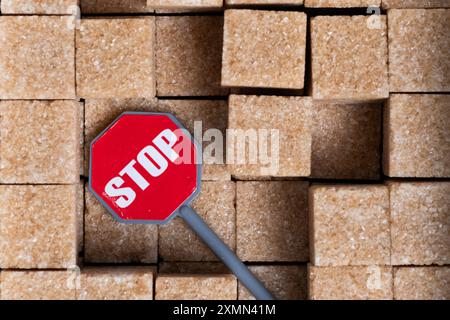 Segnale di stop sullo sfondo dei cubetti di zucchero di canna. Concetto di fermare la produzione di zucchero Foto Stock