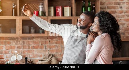 Felicemente sposata giovane tenendo selfie sullo smartphone in cucina Foto Stock
