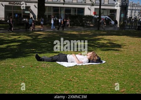 Una persona che prende il sole a Leicester Square, Londra. Le alte temperature potrebbero portare a un'ondata di caldo ufficiale, con gran parte del Regno Unito impostato per godersi "un clima molto caldo, localmente caldo" nei prossimi giorni. Data foto: Lunedì 29 luglio 2024. Foto Stock