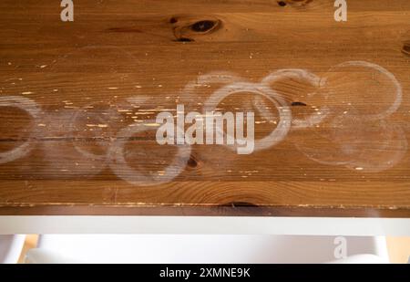 Macchie calde bianche e rotonde sul tavolo da cucina di casa, mobili in legno rovinati in casa. Foto Stock