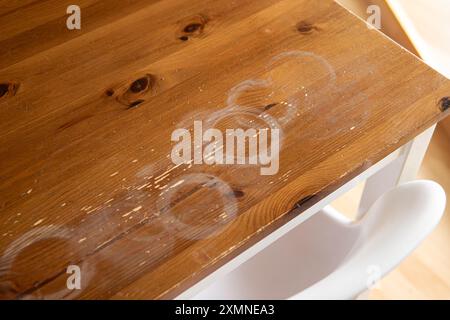 Macchie calde bianche e rotonde sul tavolo da cucina di casa, mobili in legno rovinati in casa. Foto Stock