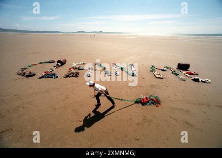 Susannah Hickling , Readers Digest Environment Editor scrive un semplice messaggio ' Pulisci me' dai rifiuti raccolti in 500 metri di una delle 250 spiagge che i volontari stanno prendendo di mira per il lancio della campagna 'Beachwatch '98' Clean Beach . Lo scorso anno oltre 2.400 volontari hanno raccolto un totale di 262.349 rifiuti, tra cui 4.243 lunghezze di rete da pesca, 8064 lattine per bevande, 1.153 contenitori per olio e detergente e 17.053 confezioni croccanti e dolci. Il cartello "Clean Beach" è composto da vecchie biciclette, reti da pesca, fusti d'olio, pneumatici per auto, bottiglie di plastica, uccelli morti, lattine di vernice e una varietà di scarti Foto Stock