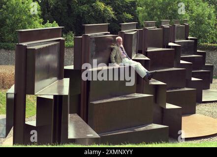 Lo scultore Sir Anthony caro siede sulla sua creazione monolitica lunga 120 metri Goodwood Steps presso la Sculpture del parco di sculture Goodwood vicino a Chichester West Sussex Inghilterra Regno Unito è la scultura più grande della Gran Bretagna. 1 settembre 1996 foto di Roger Bamber Foto Stock