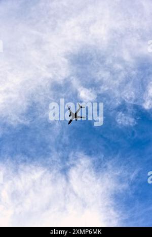 Forme astratte formate da nuvole Cirrus contro un cielo blu con la silhouette di un jet passeggeri in cielo Foto Stock