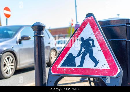 Vista ravvicinata di un cartello triangolare per lavori stradali in un parcheggio pubblico. Foto Stock